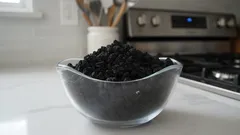 Frijoles negros cocidos en un tazón de vidrio sobre una cocina moderna.