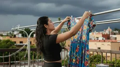 Mujer tendiendo ropa colorida en azotea bajo cielo nublado en México