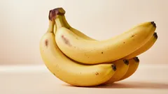 Racimo de plátanos frescos sobre fondo claro, fruta tropical saludable y nutritiva.